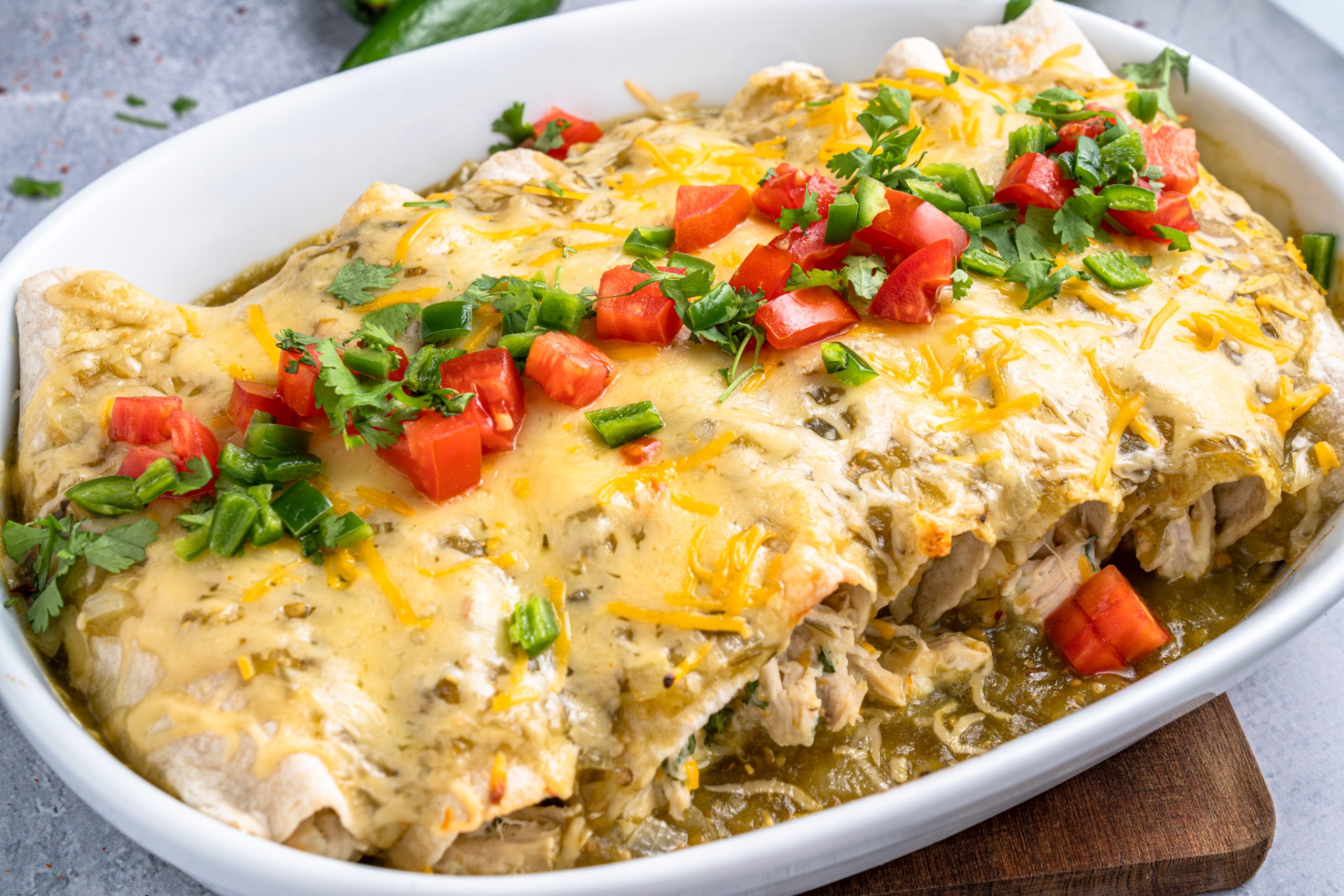 Finished chicken enchiladas with green sauce in white dish