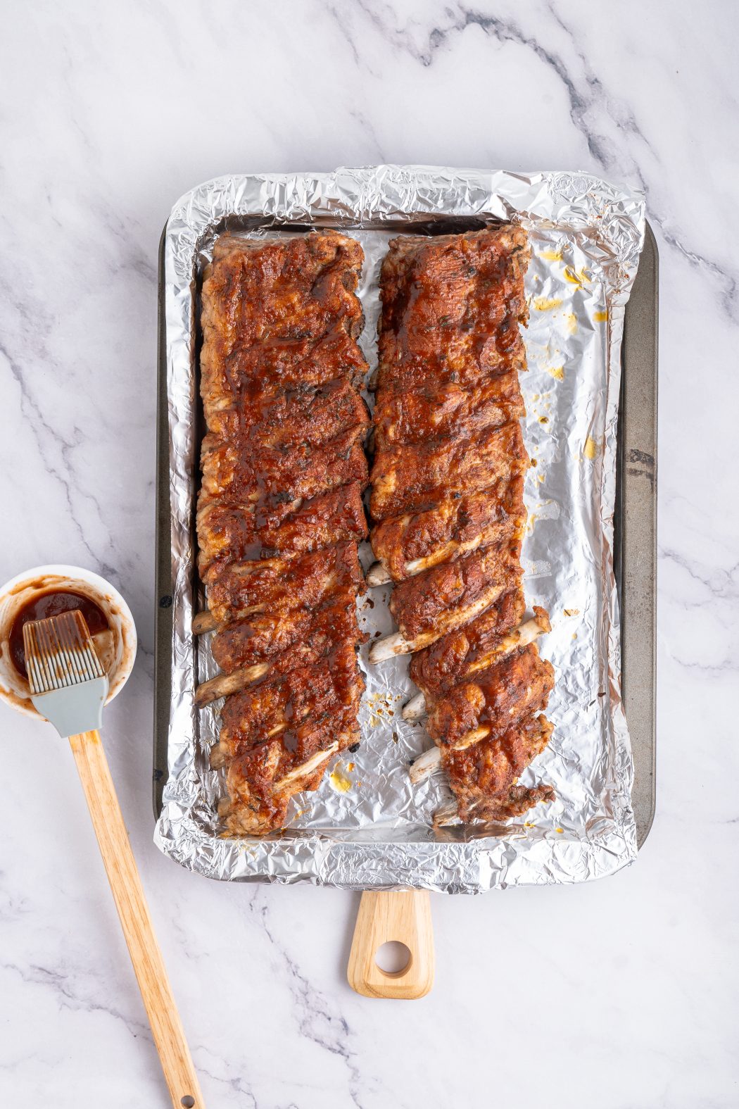 BBQ sauce on Instant pot baby back ribs on a baking tray