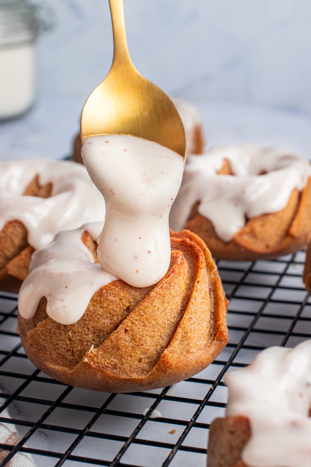 Spooning glaze onto a pumpkin bundt cake