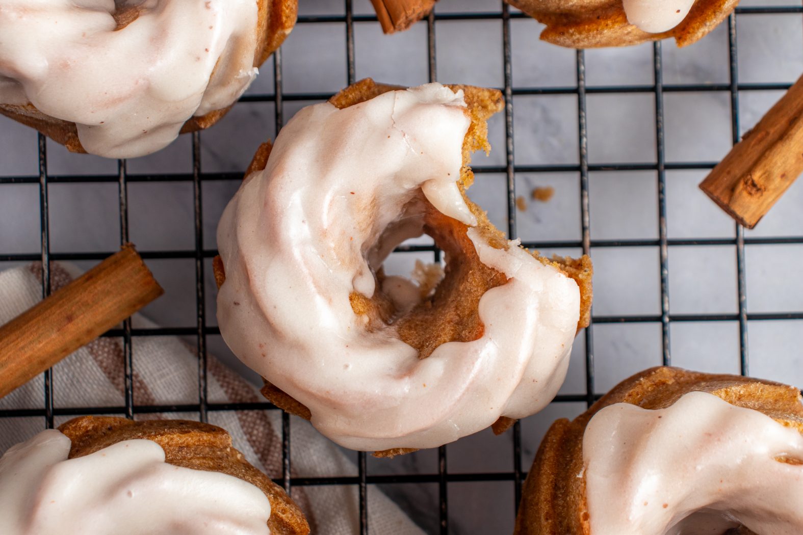 Top down view of mini pumpkin bund cakes on a cooling rack with a bite taken out of one