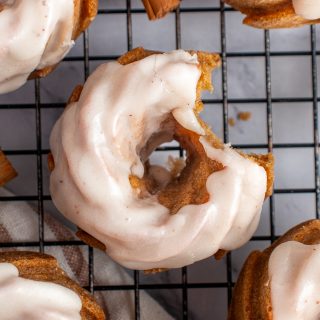 Top down view of mini pumpkin bund cakes on a cooling rack with a bite taken out of one