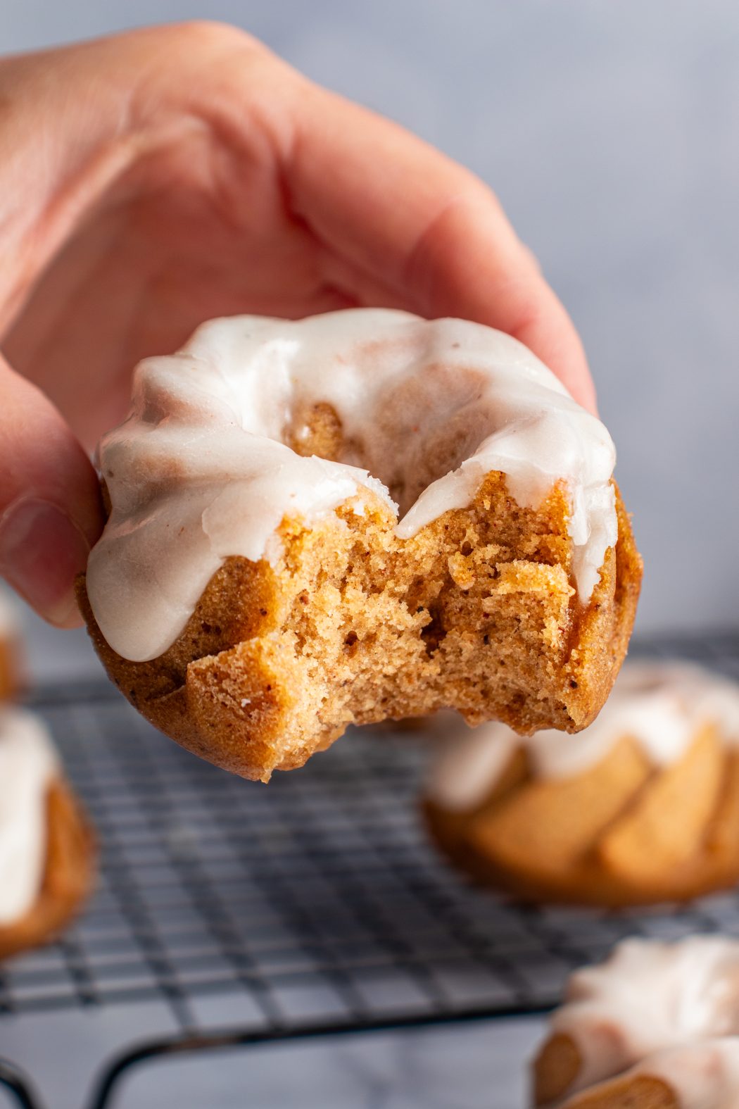 Hand holding a mini pumpkin bundt cake that has been bitten into