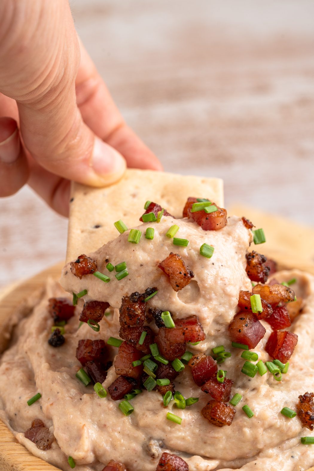 Hand dipping a cracker into bacon aioli