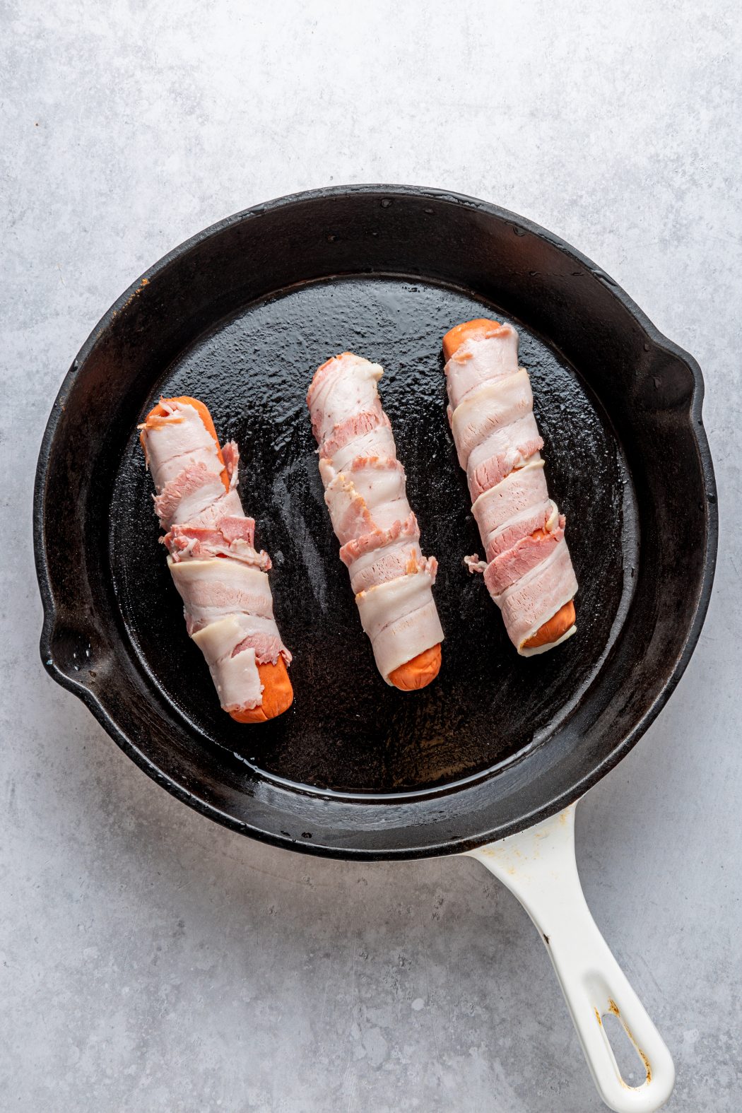 bacon wrapped hotdogs in a skillet