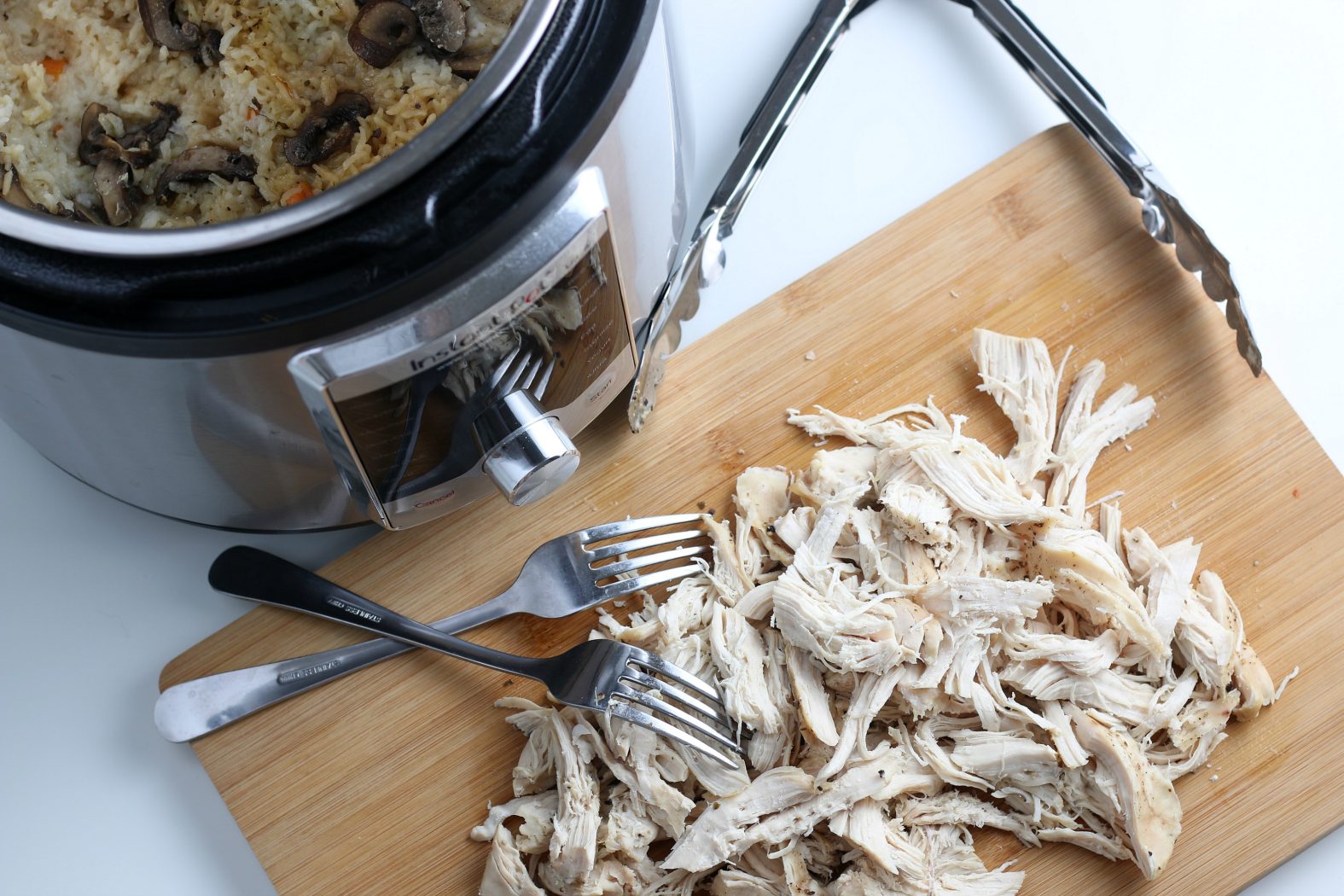 shredded chicken on a cutting board next to an Insant Pot
