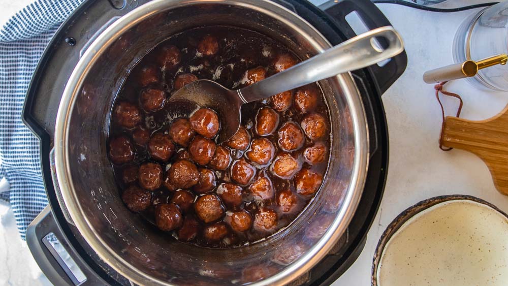 grape jelly meatballs in an instant pot with a serving spoon