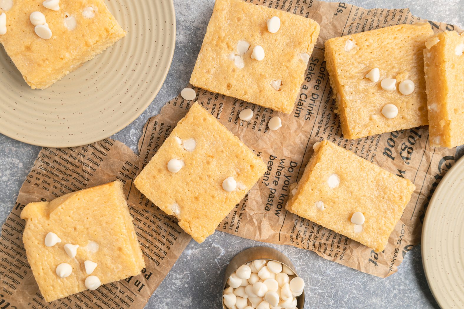 white chocolate brownies with a cup of white chocolate chips on the side